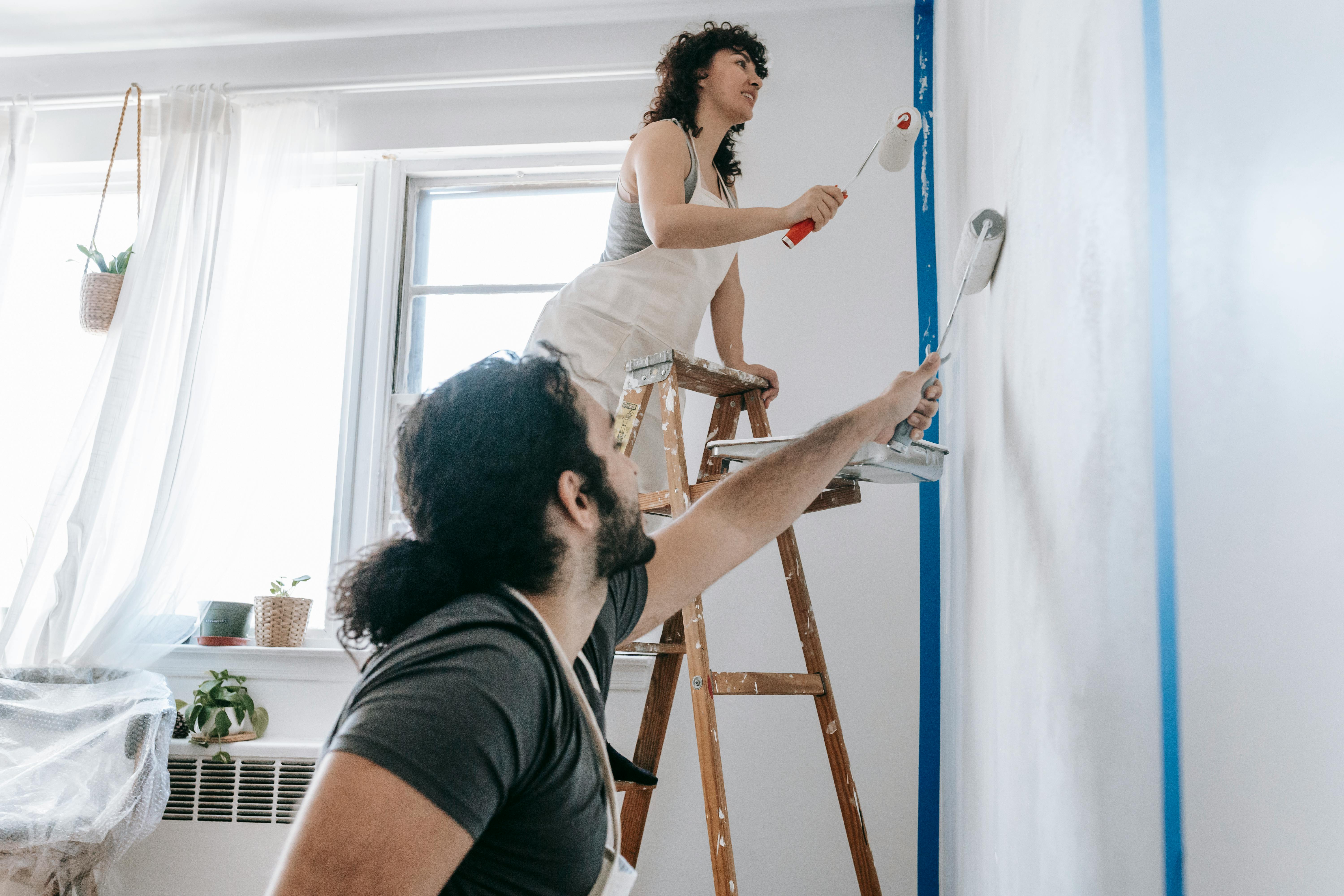 Professional painters applying wall paint using roller and brush during interior work